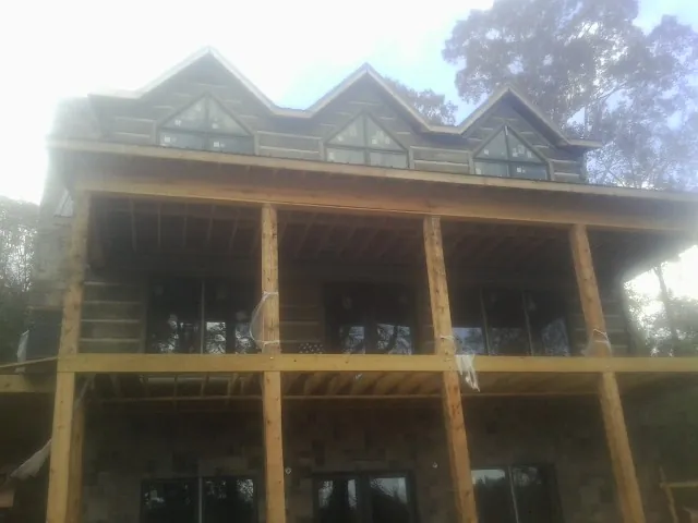 Dormers and porch framing on a large log home under construction — Roof Coating work by our crew in New Castle