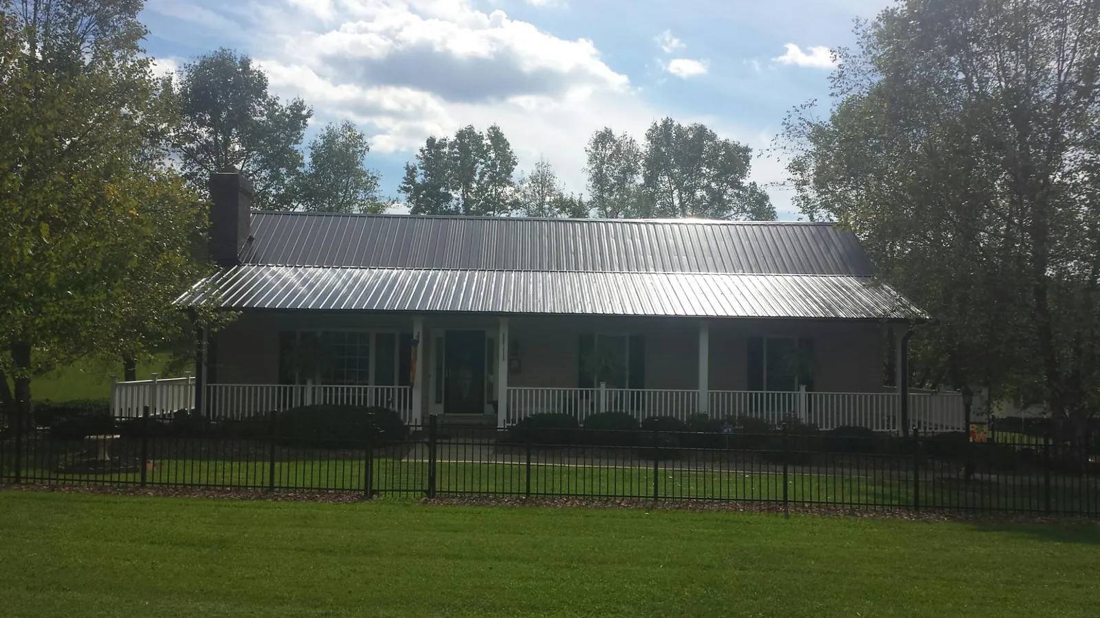 Gray metal roof on a brick ranch with a full width front porch — Gutter Guard Installation work by our crew in New Castle